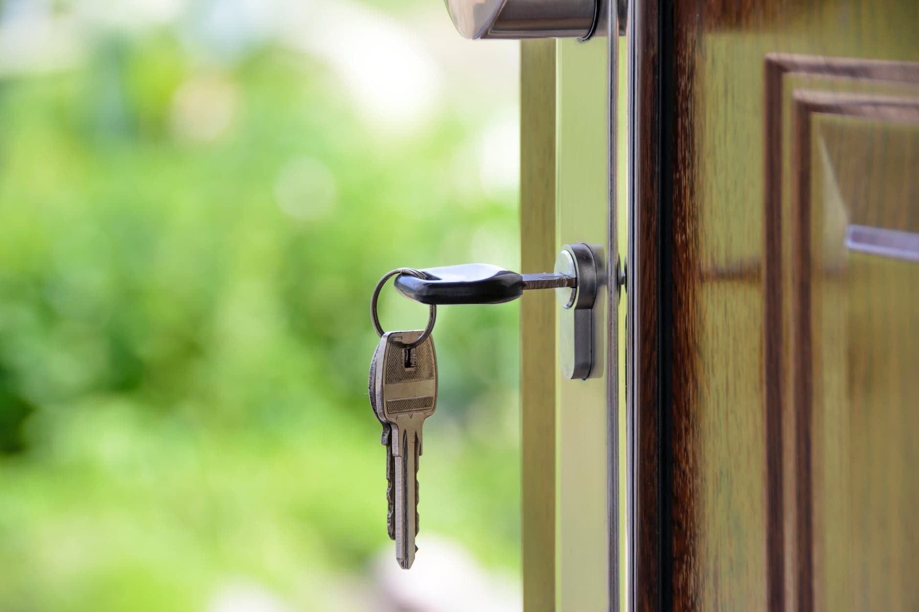 A key with a key ring hanging from the lock of a door